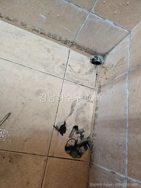 벽 수전을 떼어낸 뒤 타일 벽면에 남은 급수배관 입구와 바닥의 부속 잔해