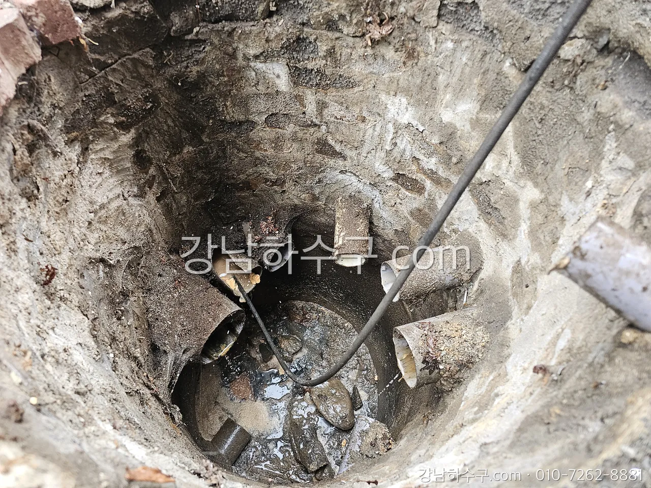 슬러지가 차오른 맨홀 안에 준설 호스를 넣은 모습